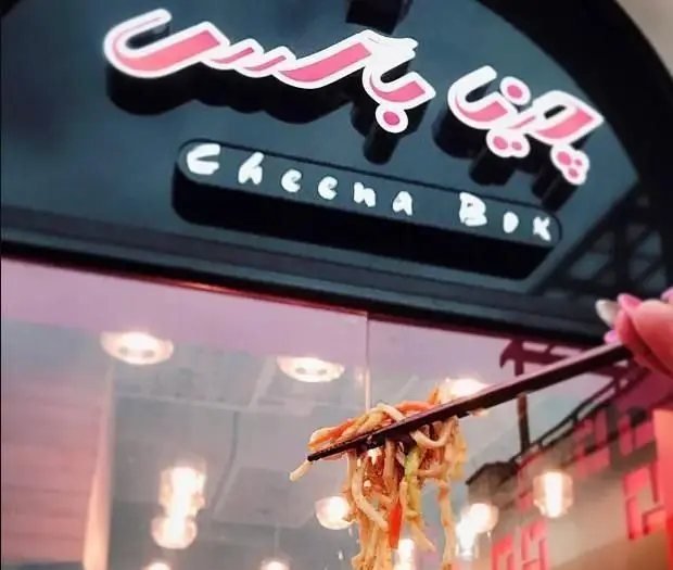 تصویری جذاب از تابلوی رستوران "چینا باکس" با لوگوی فارسی و انگلیسی، به همراه نودل داغ سرو شده با چاپستیک که نشان از غذای چینی دارد.