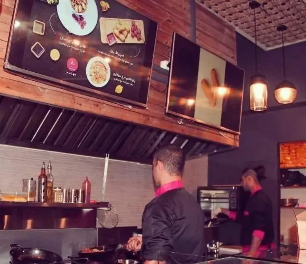 رستوران چینی چینا باکس: آشپزخانه پر جنب و جوش با سرآشپزها در حال طبخ نودل و اسپرینگ رول، همراه با منوی دیجیتال.