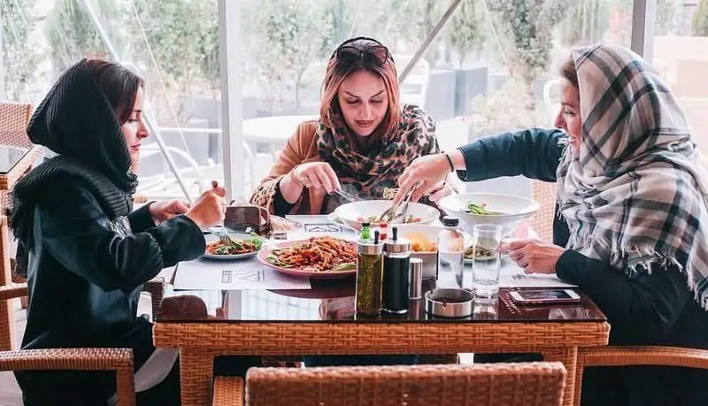 مشتریان شاد در کافی شاپ دلچی مشغول صرف ناهار و گپ زدن. محیطی دلنشین برای دوستان و خانواده با منوی متنوع غذا و نوشیدنی.