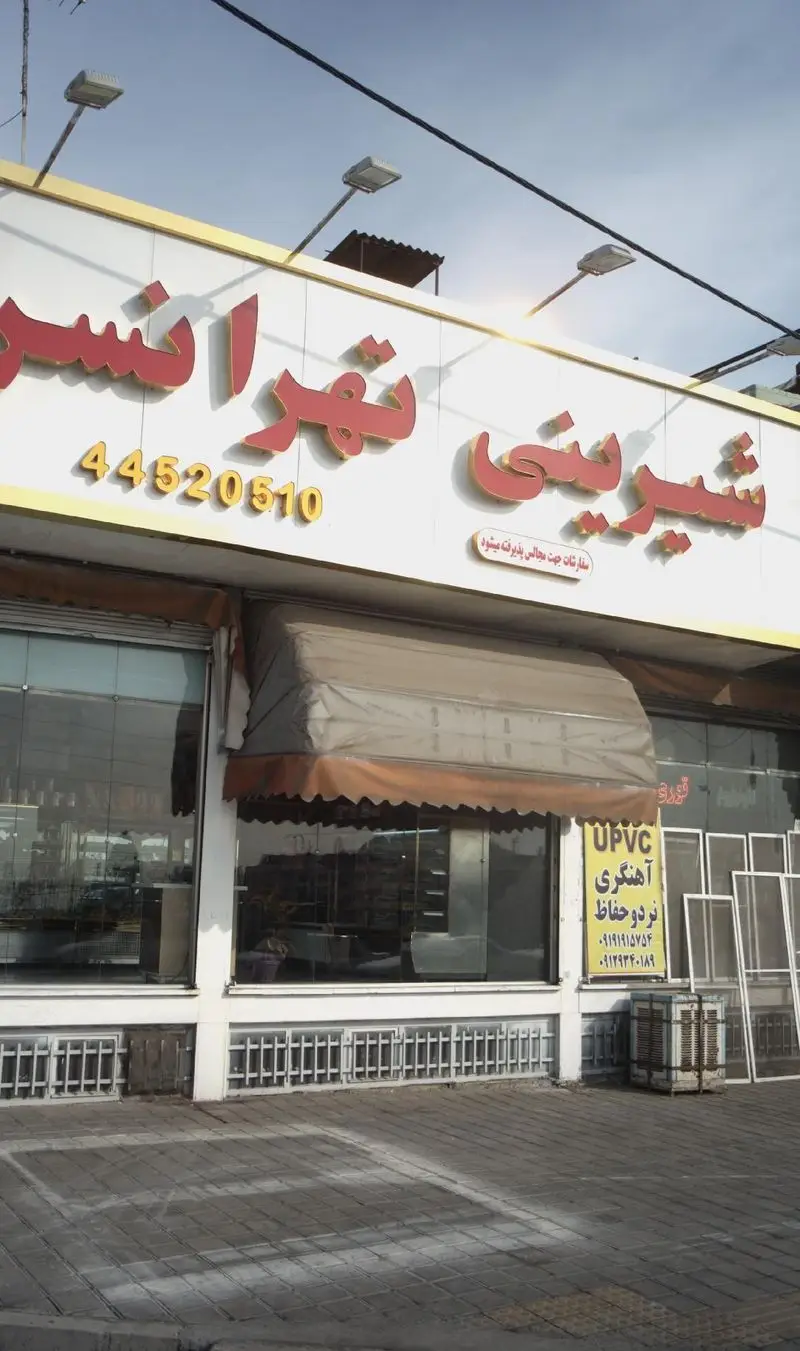 نمای بیرونی شیرینی تهرانسر، یک قنادی بزرگ با تابلوی قرمز رنگ، شماره تلفن 44520510 و متن پذیرش سفارشات مجالس و اعیاد.