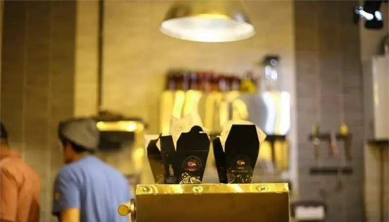 نمایی از فضای داخلی مدرن و جذاب پیتزایی پادلا، با تمرکز بر جعبه‌های بسته‌بندی شیک غذا روی پیشخوان آماده سرویس.