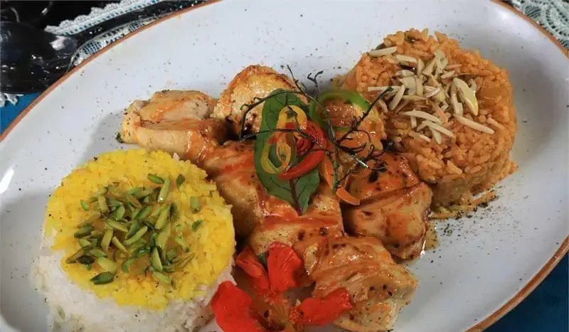 غذای اصیل رستوران مراکش الجزایر: جوجه کباب با پلو زعفرانی و پسته، به همراه برنج نارنجی با تزئین بادام. تجربه‌ای خوشمزه.
