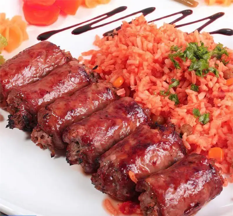 کباب رولی آبدار و برنج قرمز معطر، غذای محبوب مراکشی-الجزایری در رستوران با طعم‌های اصیل.