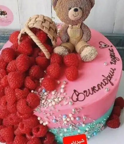 کیک تولد شیک صورتی و آبی با خرس تدی، سبد پر از تمشک‌های تازه و آبنبات، مناسب اولین سالگرد از شیرینی دلوین.