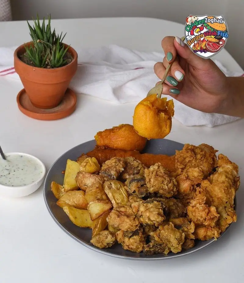 سینی جذاب چیکن ذغالی: مرغ و قارچ سوخاری، سیب‌زمینی و اسنک‌های سرخ شده، آماده برای لذت بردن از طعم بی‌نظیر. منوی کامل و متنوع فست فود.