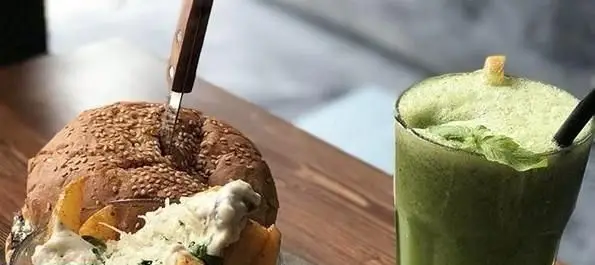 تصویری جذاب از برگر مخصوص ویتندی با پنیر و اسموتی سبز خنک، نمادی از تجربه غذایی دلپذیر در رستوران ایتالیایی ویتندی.