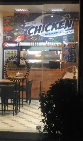 نمای شبانه فود نیکو، رستوران فست فود مرغ سوخاری. طراحی داخلی با دیوارنگاری "Fried Chicken DELICIOUS FRESH" و یخچال پپسی.