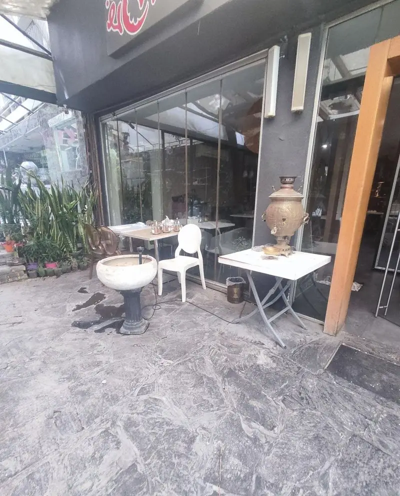 نمای بیرونی طباخی کلپچ خوب با میز و صندلی در فضای باز، گلدان‌ها و سماور دکوری. مکانی مناسب برای سرو کله‌پاچه.