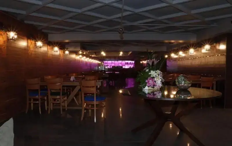 محیط شیک و دنج رستوران فرنگی کاریان با نورپردازی خاص، دیوار چوبی، میز و صندلی چوبی و بار مدرن در انتها.