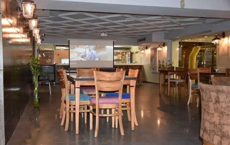 فضای داخلی دنج و مدرن رستوران فرنگی کاریان با میز و صندلی‌های چوبی و صفحه نمایش پروژکتور برای تماشای فیلم در محیطی دلنشین و آرام.