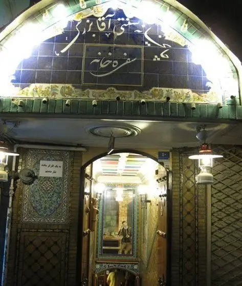 ورودی جذاب سفره خانه آقا بزرگ، با سردر کاشی‌کاری سنتی آبی رنگ و خوشنویسی زیبای فارسی، فضایی دلپذیر برای تجربه غذای ایرانی.