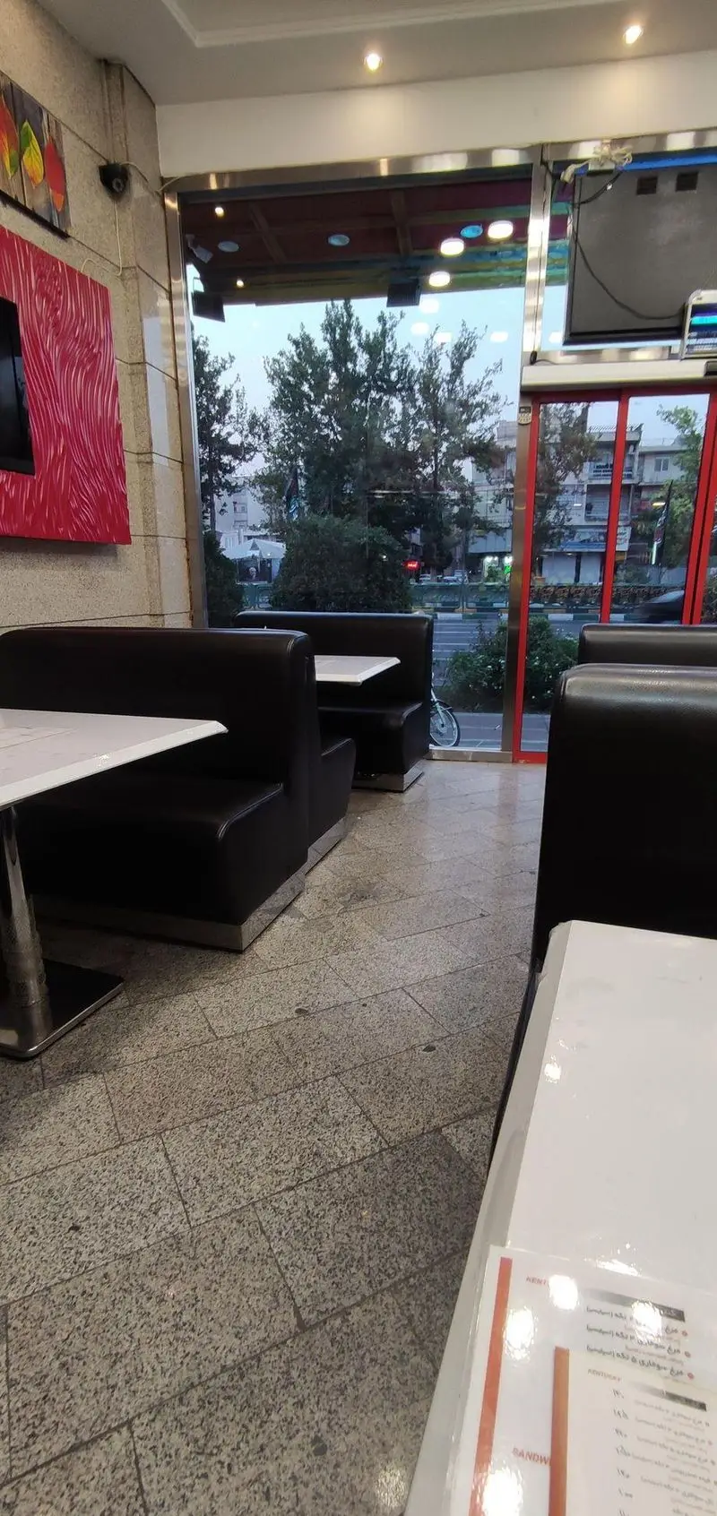 تصویر دکوراسیون داخلی فست فود پیتزا دلفین، با صندلی‌های بوث مشکی و میزهای سفید، محیطی شیک و تمیز مناسب برای یک تجربه غذایی دلنشین در قلب شهر.