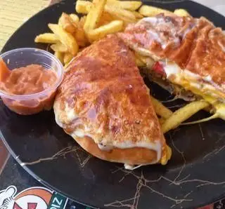 ساندویچ گریل شده پنیری نصف شده همراه با سیب زمینی سرخ کرده طلایی و سس قرمز در ظرف کوچک از پیتزا پاریز.