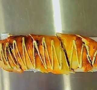 ساندویچ یا نان ویژه پیتزا پاریز، با رویه طلایی برشته، تزئین شده با سس سبز و آماده سرو در برش‌های جذاب.