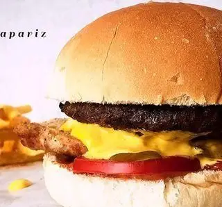 چیزبرگر خوشمزه رستوران پیتزا پاریز با پنیر، گوجه، گوشت آبدار، نان تازه و سیب‌زمینی سرخ‌کرده، لذت غذای سریع.