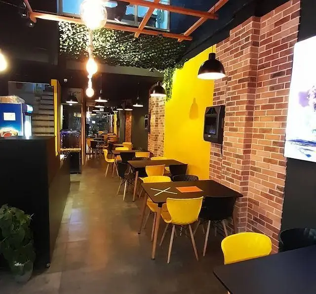 محیط داخلی شیک و دلنشین رستوران پیتزا ساندویچ ورنا با دکوراسیون مدرن، میز و صندلی‌های رنگی و نورپردازی زیبا.