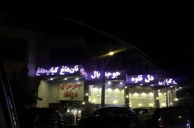 تابلوهای نئونی درخشان رستوران کبابی جگرسرای دولت در شب، با منوی نان داغ کباب داغ، جوجه بال و دل قلوه.