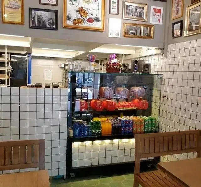 فضای داخلی رستوران پر پل سوخاری با پیشخوان کاشی‌کاری شده، یخچال نمایش نوشیدنی و غذاهای آماده مانند مرغ سوخاری