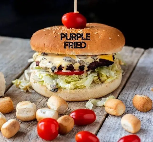 برگر لذیذ پر پل سوخاری با پنیر ذوب شده و قارچ، کاهو تازه و گوجه فرنگی روی میز چوبی. بهترین فست فود سوخاری.