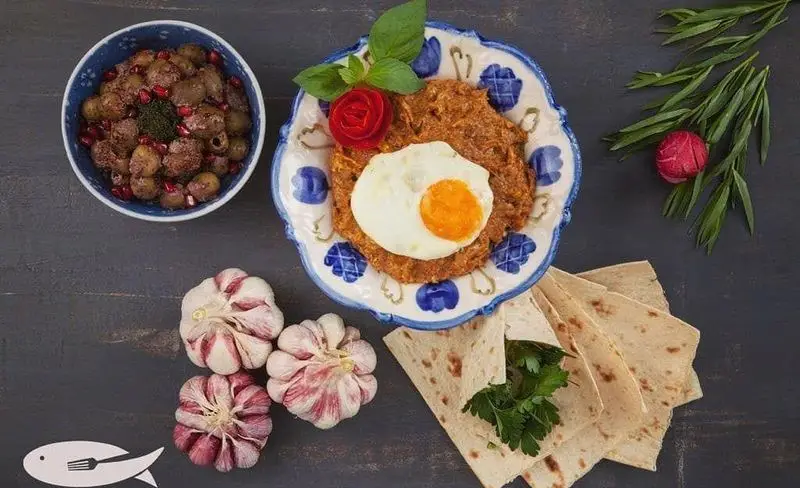 رستوران ماهی سفید: سفره ای دلنشین از غذای سنتی ایرانی؛ میرزا قاسمی با تخم مرغ، زیتون پرورده، نان محلی، سیر و سبزیجات تازه.