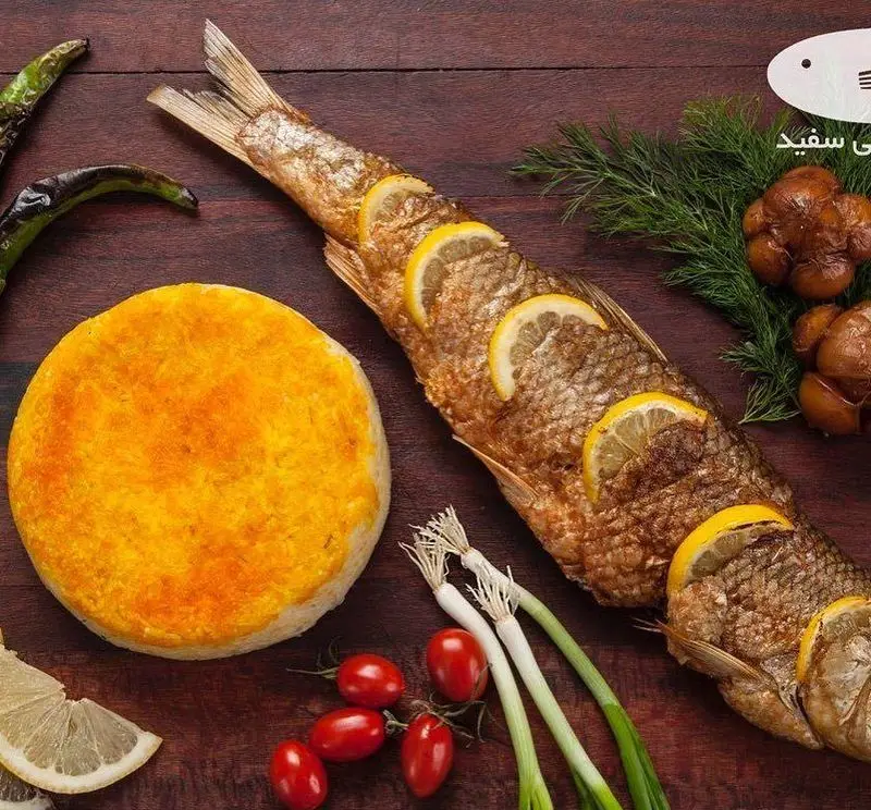 ماهی سفید برشته با لیمو، ته دیگ زعفرانی خوشرنگ، گوجه، پیازچه و فلفل از بهترین رستوران ماهی سفید. غذای سنتی ایرانی.