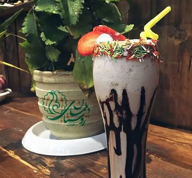 شیک توت فرنگی با اسپرینکلز و سس شکلات در سفره خانه و کافه روستای دیلمان. تجربه نوشیدنی‌های خوشمزه در فضایی دلنشین.