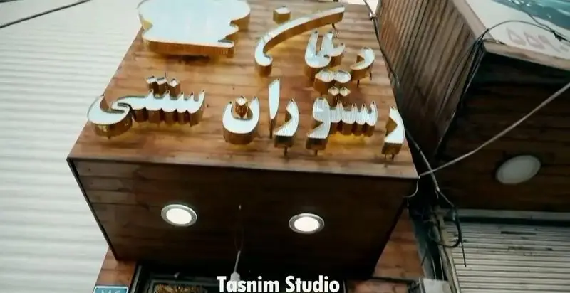 تابلوی ورودی سفره خانه سنتی، کافه و رستوران دیلمان، با حروف برجسته طلایی روی پس زمینه چوبی، مکانی دنج در روستای دیلمان.