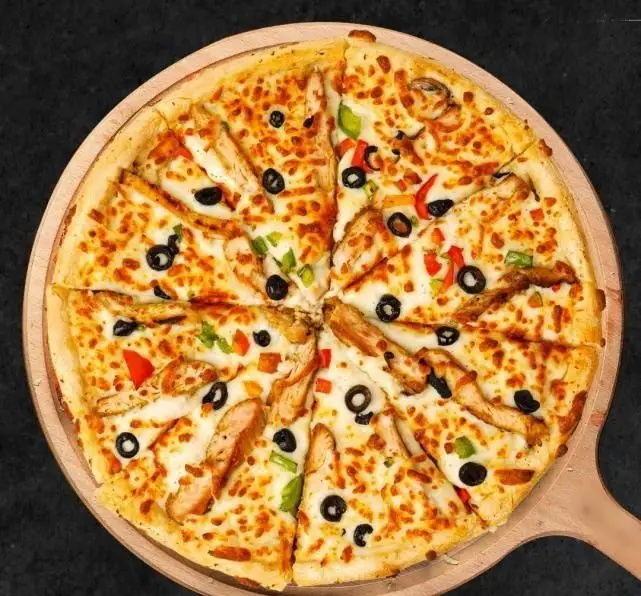 پیتزا مرغ و سبزیجات تازه تله پیتزا روی سینی چوبی. این پیتزا با تکه‌های مرغ، زیتون سیاه، فلفل دلمه‌ای رنگی و پنیر فراوان سرو می‌شود.