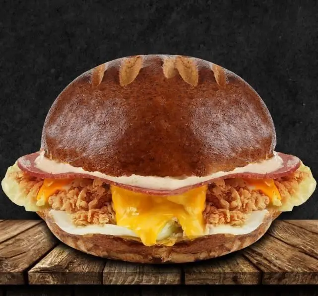 ساندویچ خاص تله پیتزا: مرغ سوخاری ترد، پنیر چدار ذوب شده، گوشت فراوری شده و سس ویژه در نان برگر قهوه‌ای، آماده برای سفارش.