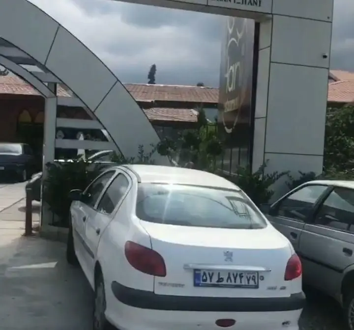 نمای ورودی و خارجی رستوران هانی مطهری با طراحی آرک مدرن، تابلو مجموعه و خودروهای مشتریان در پارکینگ مجموعه.