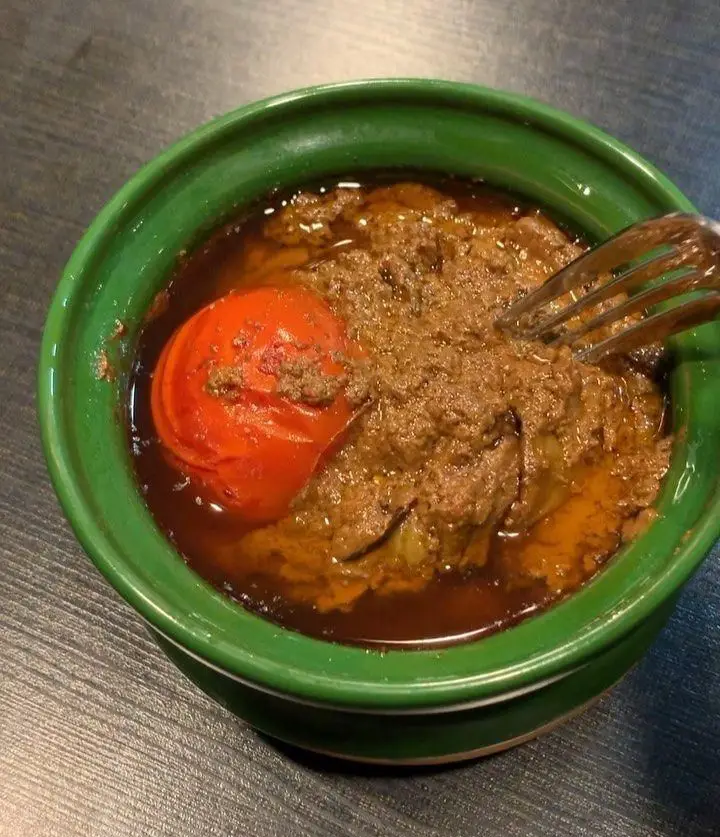 تصویری از خورش ایرانی لذیذ با سس غلیظ و گوجه فرنگی، سرو شده در کاسه‌ای سبز. غذای سنتی رستوران هانی مطهری.