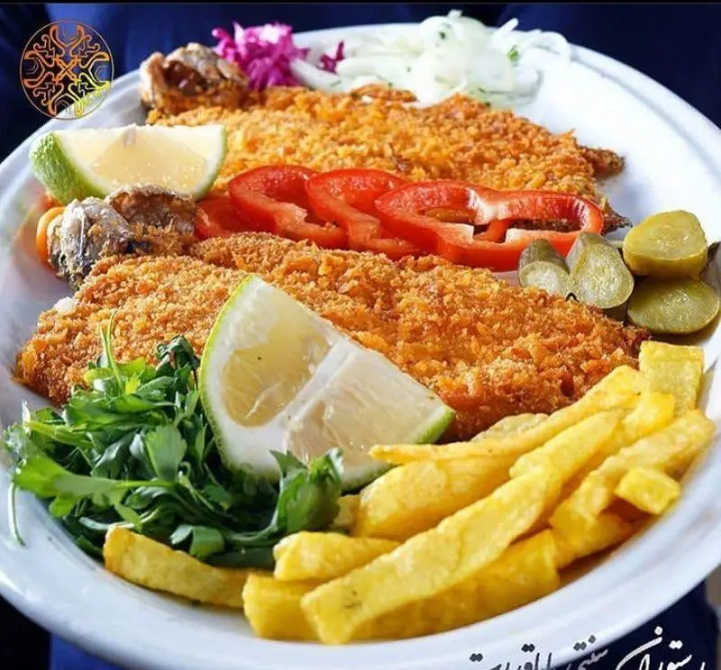 تصویری جذاب از فیله ماهی سوخاری ترد و خوشمزه رستوران سنتی عقیق بابا قدرت با دورچین سیبزمینی سرخکرده، لیمو و سبزیجات