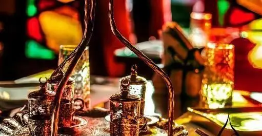 نمایی نزدیک از ظروف شیک و سنتی برنجی و مسی برای سرو قهوه و چای در کافه رستوران هترا، تجربه‌ای دلنشین در فضایی با دکوراسیون خاص و نورپردازی گرم.