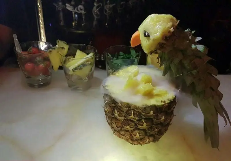 کوکتل آناناس طوطی‌شکل با دود خشک در کافه رستوران هترا، نمایشی جذاب از میوه‌های تازه و نوشیدنی‌های فصلی و خاص.