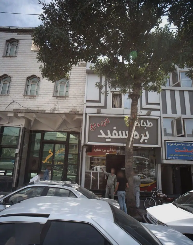 تصویر نمای خارجی طباخی بره سفید، یک رستوران معروف ایرانی در خیابان‌های شلوغ تهران که غذاهای سنتی و کله پاچه ارائه می‌دهد.