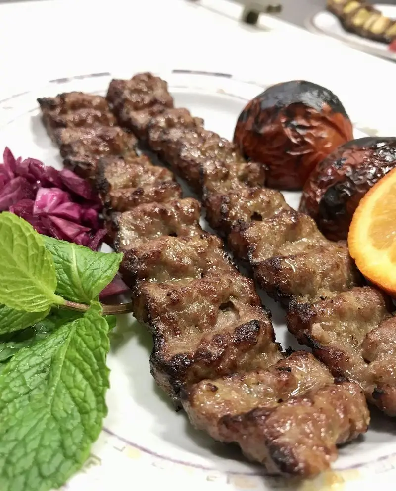 کباب کوبیده گریل شده رستوران مددی با گوجه کبابی، نعناع تازه، برش پرتقال و ترشی. طعم اصیل غذای ایرانی را تجربه کنید.