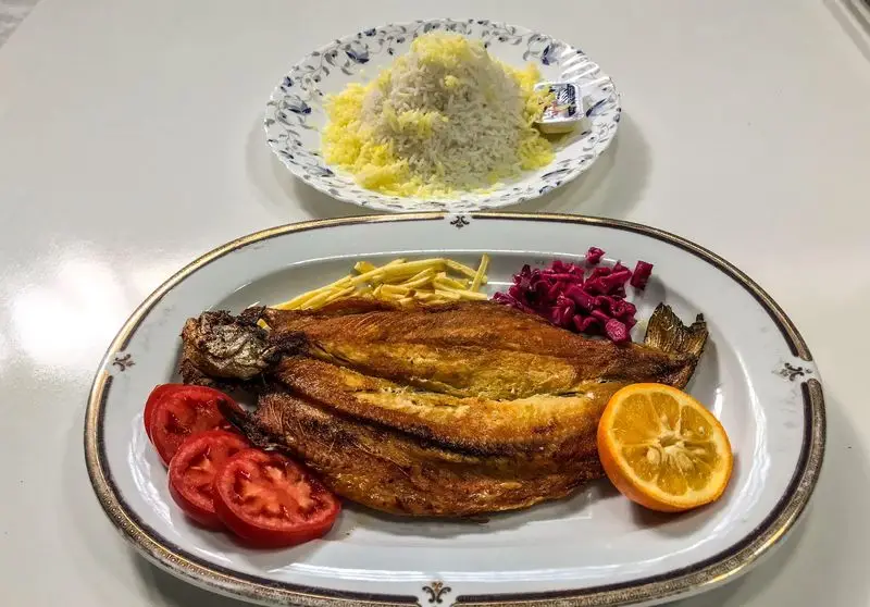 چلو ماهی سرخ شده کامل به همراه برنج زعفرانی، گوجه، ترشی و پرتقال در رستوران مددی، طعمی فراموش‌نشدنی.