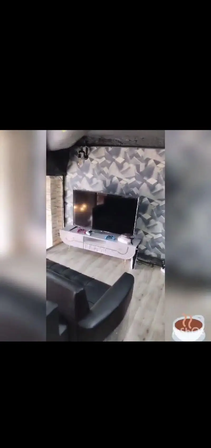 دکوراسیون شیک کافه گیم پاتوق با دیوارپوش مدرن، تلویزیون بزرگ، کنسول بازی و مبل چرمی ایده‌آل برای بازی و استراحت.