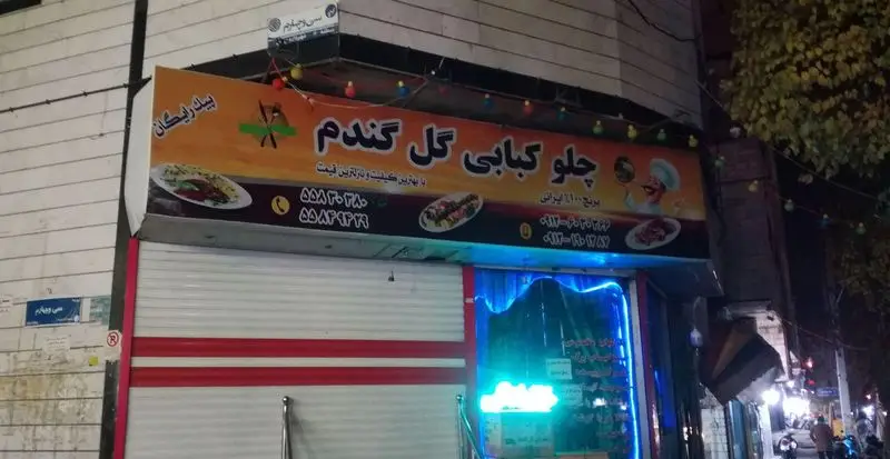 نمای خارجی رستوران چلو کبابی گل گندم در شب با تابلوی تبلیغاتی کباب، برنج ایرانی، کیفیت عالی، قیمت مناسب و پیک رایگان.