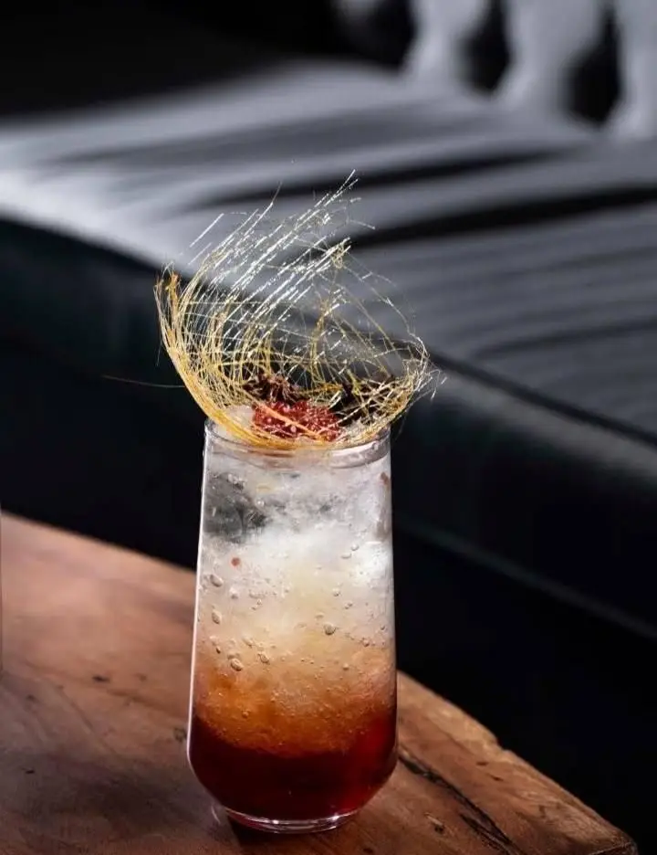 کوکتل یا نوشیدنی لایه ای ویژه بالکافه با رنگ های گرم و گارنیش هنری کارامل و توت. تجربه‌ای دلپذیر در کافه.