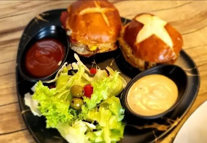 منوی بالکافه: دو برگر لذیذ با نان پرتزل، سالاد تازه شامل کاهو، زیتون و گوجه، به همراه دو سس خوش‌طعم.