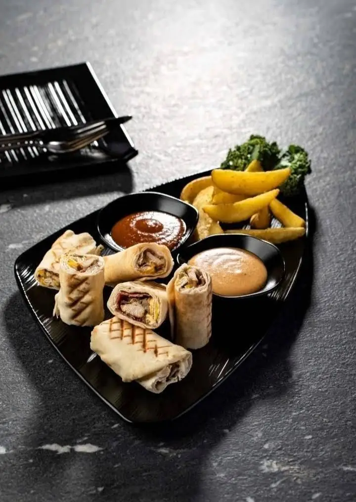 غذاهای بالکافه: سینی متنوع رپ های مرغ و پنیر، سیب زمینی تنوری و دو نوع سس مخصوص. تجربه طعمی بی‌نظیر برای هر سلیقه.