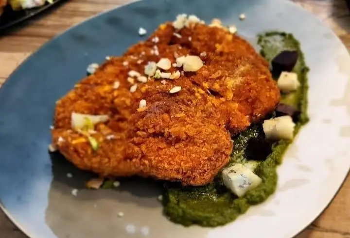 مرغ سوخاری ترد و لذیذ بالکافه، سرو شده با سس سبز معطر، پنیر سفید مکعبی و تکه‌های سبزیجات، غذایی اشتهاآور و خاص.