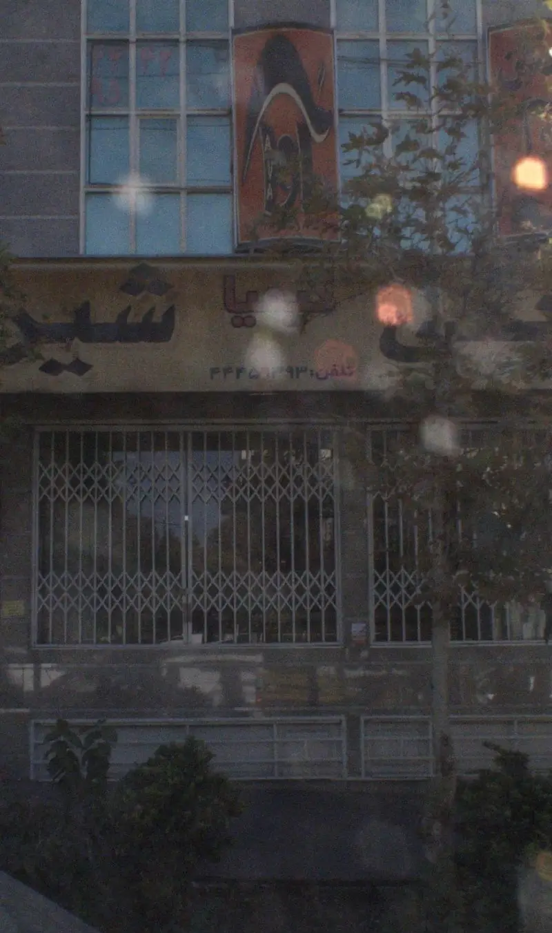 نمای بیرونی قنادی شیرینی کیمیا، شامل تابلوی فروشگاه، شماره تماس ۴۴۴۵۳۹۹۳ و درب‌های کرکره‌ای بسته با پنجره‌های بالایی.