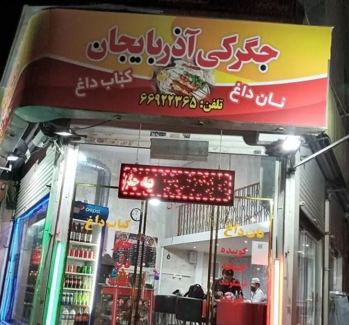 عکس از نمای بیرونی رستوران جگرکی آذربایجان با تابلوهای نان داغ، کباب داغ و شماره تلفن، آماده ارائه جگر و کباب کوبیده.