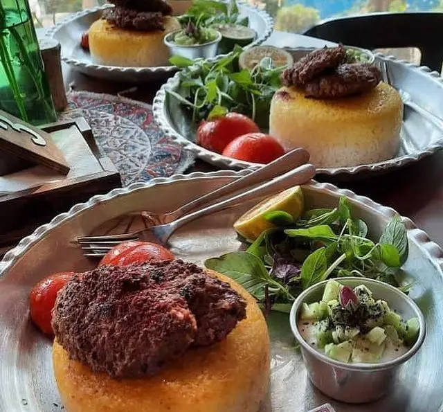 ته چین زعفرانی با کباب یا کتلت، سالاد و ماست و خیار در کافه گرین موزه مقدم. لذت غذای سنتی ایرانی در فضایی دلنشین و زیبا.