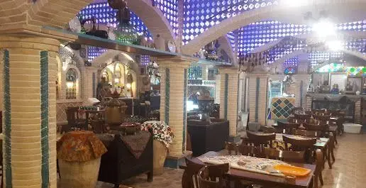 فضای داخلی دنج و سنتی کافه قلیان پیر بابا با دکوراسیون دلنشین و میزهای چیده شده آماده پذیرایی از مشتریان.