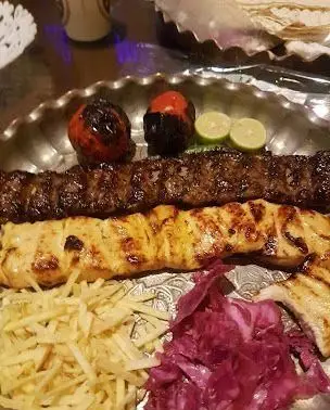 سینی کباب کوبیده و جوجه کباب لذیذ ایرانی به همراه گوجه کبابی، لیمو و دورچین، از منوی کافه قلیان پیر بابا برای یک تجربه غذایی دلپذیر.