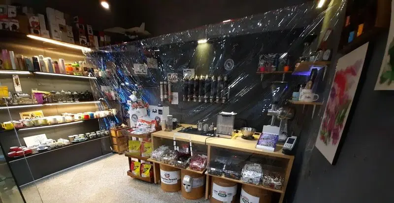 فضای داخلی سپهر کافی: نمایش محصولات متنوع قهوه شامل دانه، لوازم جانبی، و سیستم‌های قهوه سرد، با قفسه‌های منظم و نورپردازی جذاب.