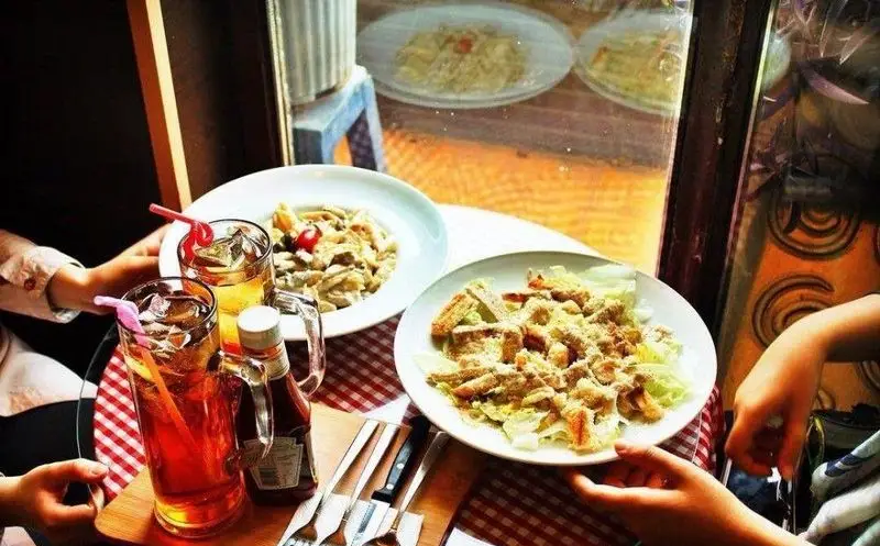 تصویری از میز کافه گرامافون: پاستای خوشمزه، سالاد سزار، نوشیدنی‌های خنک و چیدمان صمیمی. محیط دلنشین برای مشتریان.